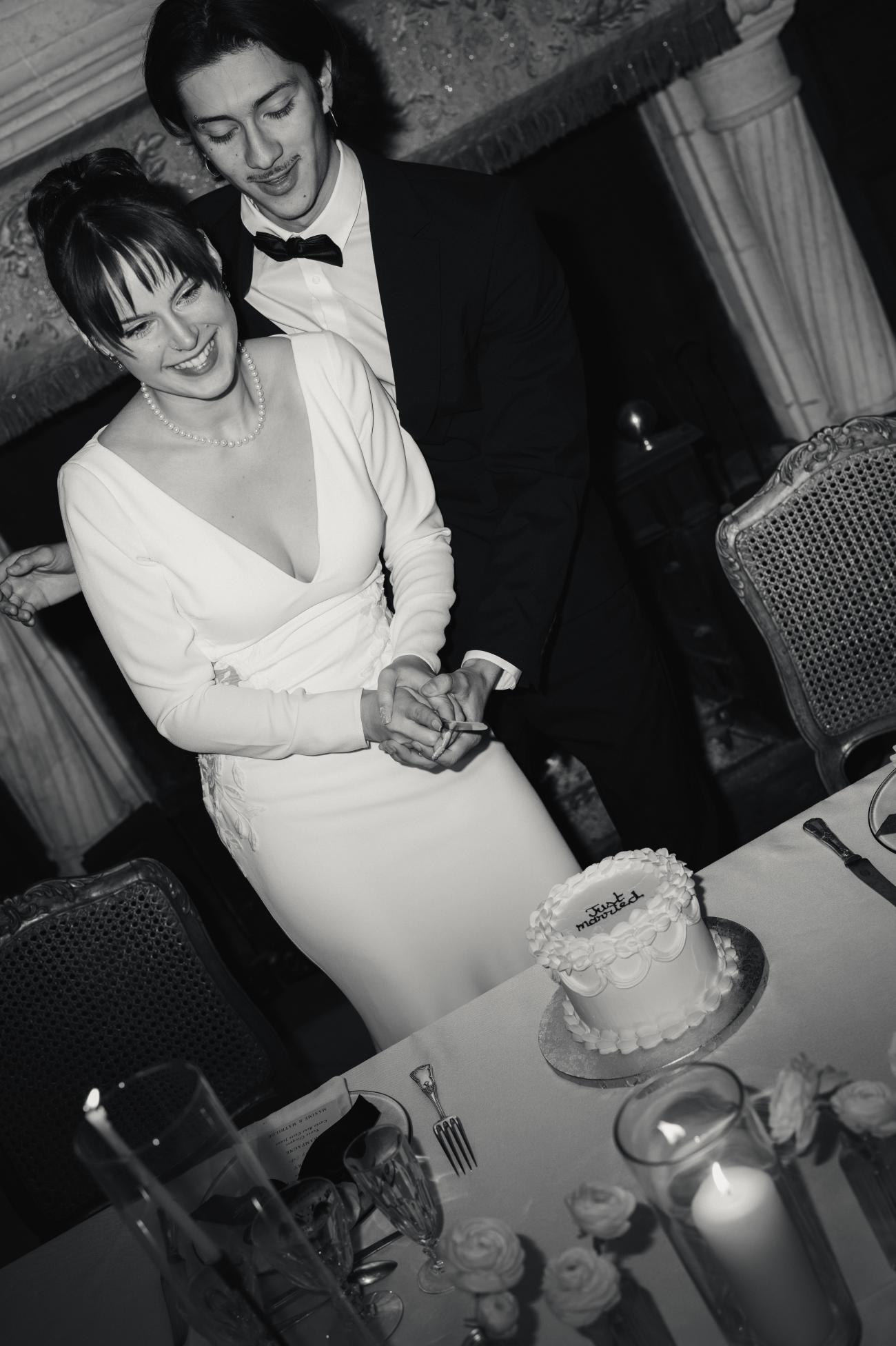 Couple de mariés lors de la découpe du gâteau de leur mariage qui a été créé par Rose Gourmande à Pau. Le couple est complice, la photo est en noir et blanc et est éditoriale. 